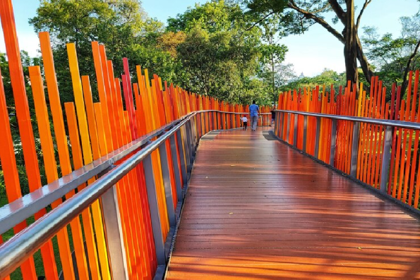 A wooden bridge with orange fence and a man walking across it.