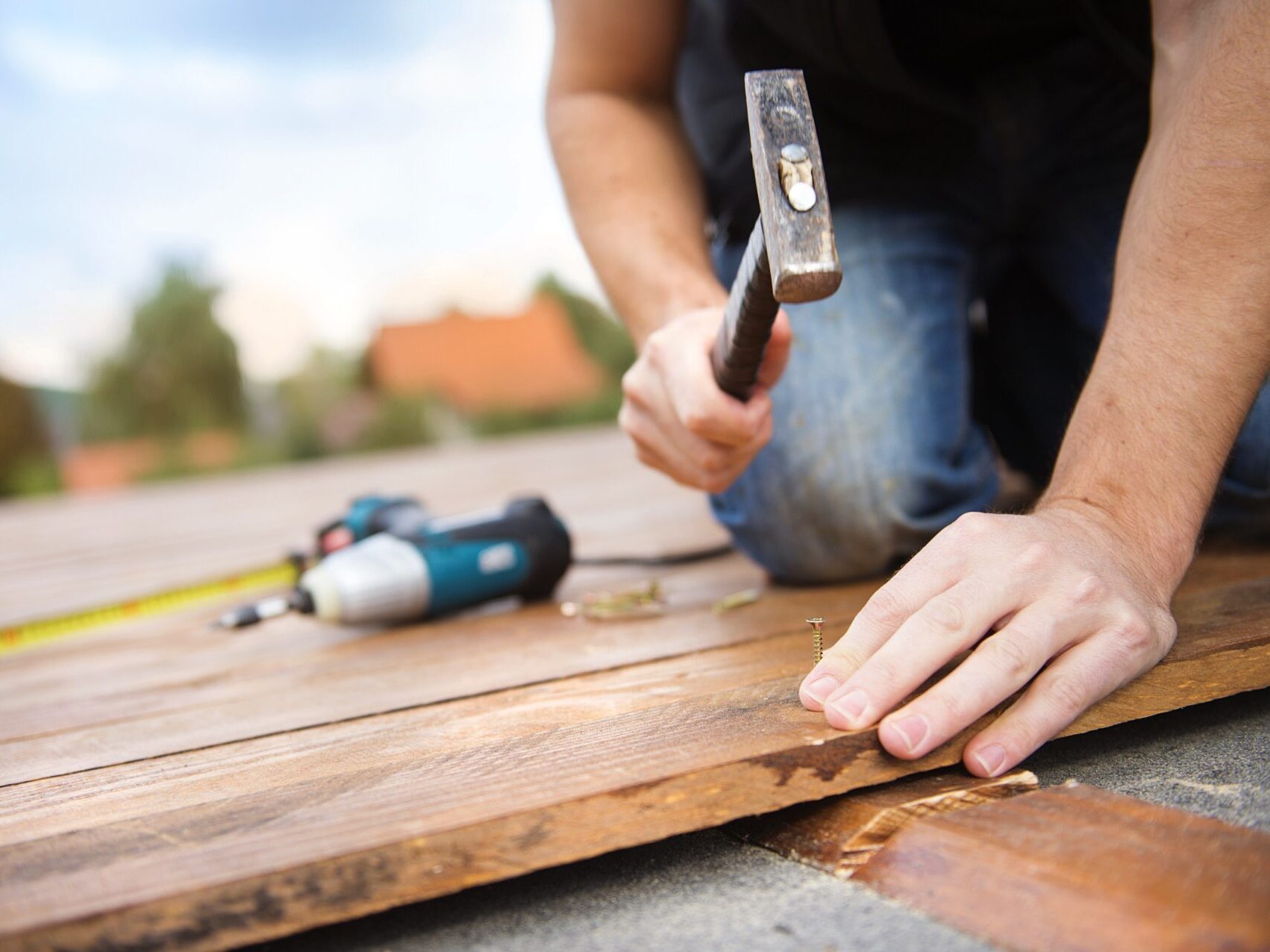 Deck construction builder hand with electric screwdriver installing impregnated wooden boards